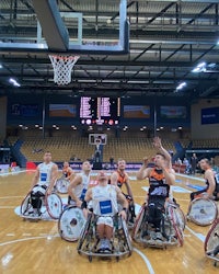 a group of men in wheelchairs on a basketball court
